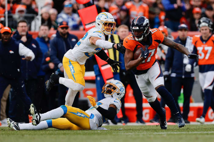 Denver Broncos wide receiver Lil'Jordan Humphrey (17) runs through the tackle of Los Angeles Chargers safety Alohi Gilman (32) and cornerback Essang Bassey (27) in the second quarter at Empower Field at Mile High.